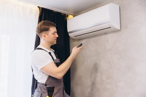 Technician installing a wall mounted air conditioning unit in a residential home